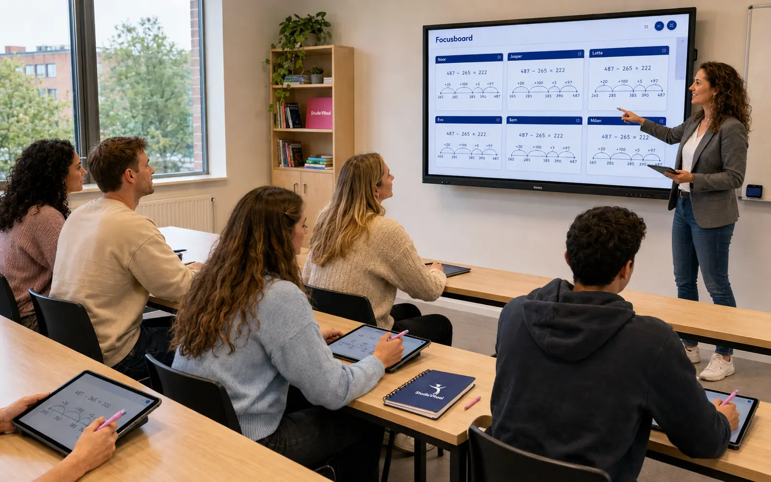 Pabostudenten werken met roze StudieVitaal-stylussen op tablets tijdens een actieve Focusboard-les. fetchpriority=